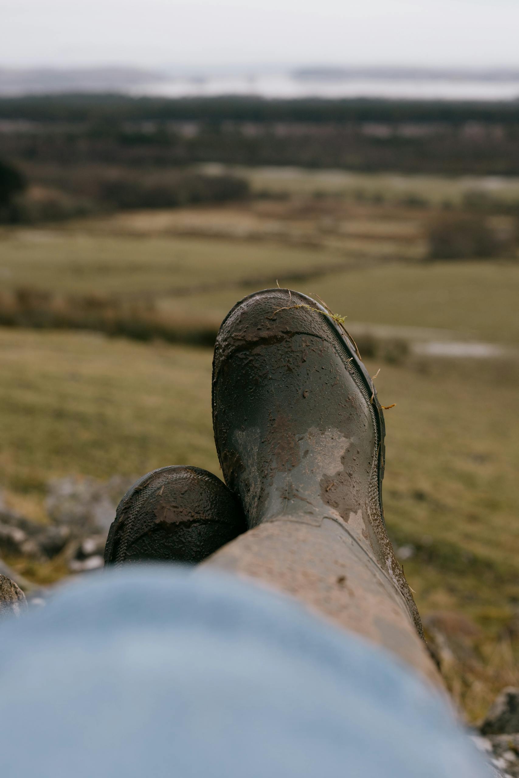 Muddy boots resting on a hillside, overlooking a scenic Scottish landscape in Inchindown.