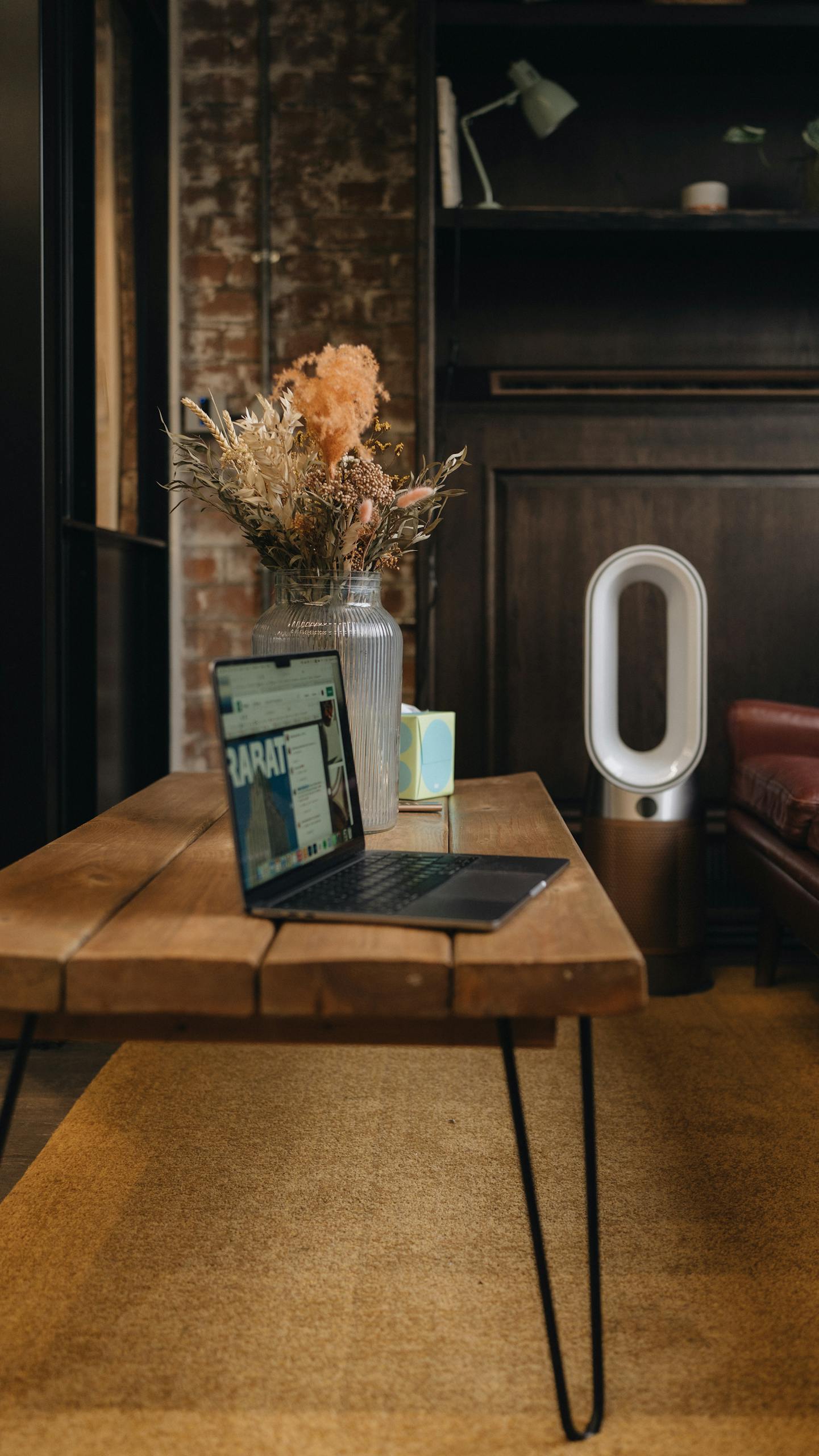 Stylish London loft workspace featuring a laptop, wooden table, and modern decor accents.