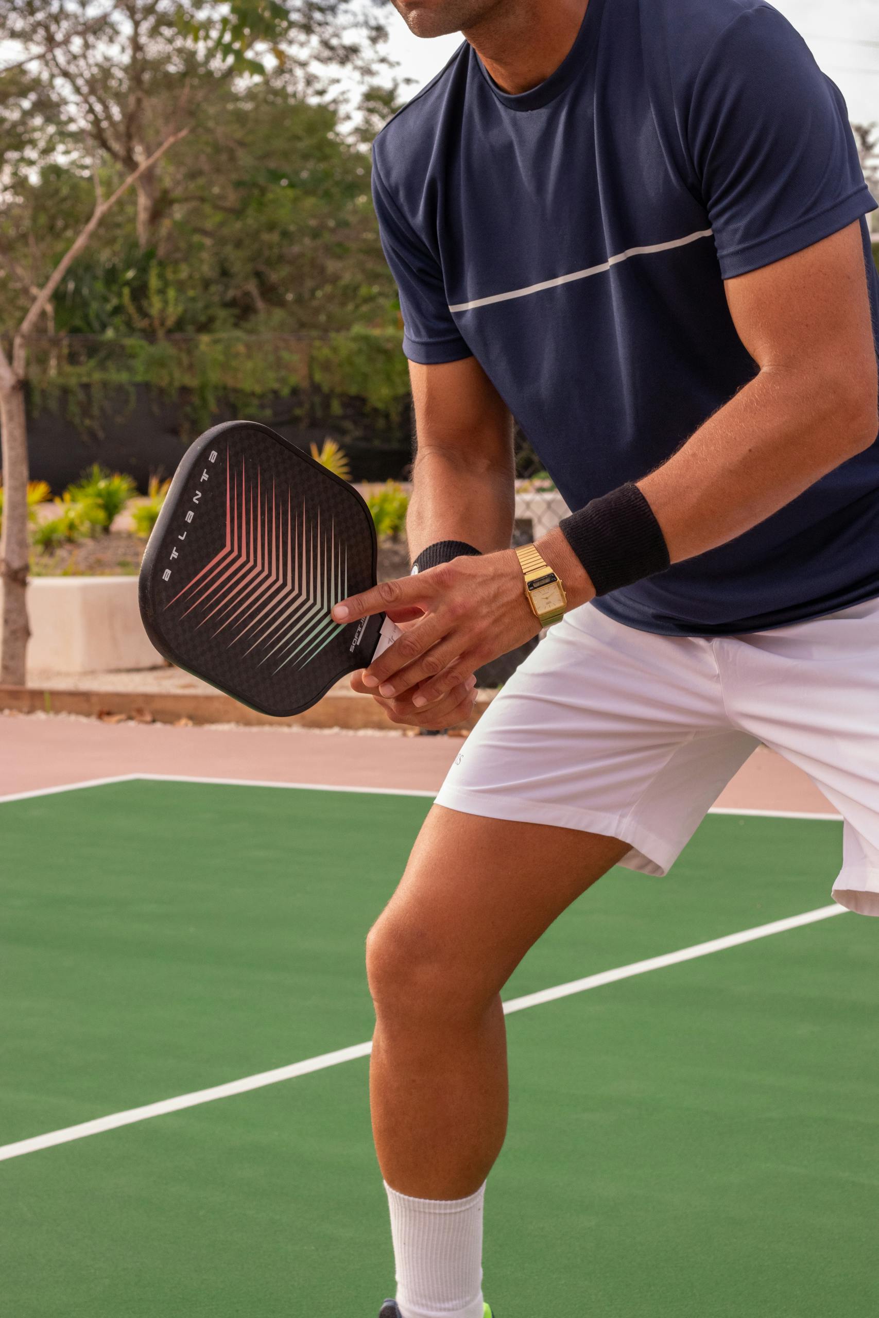 Athlete playing pickleball outdoors with paddle and ball on court