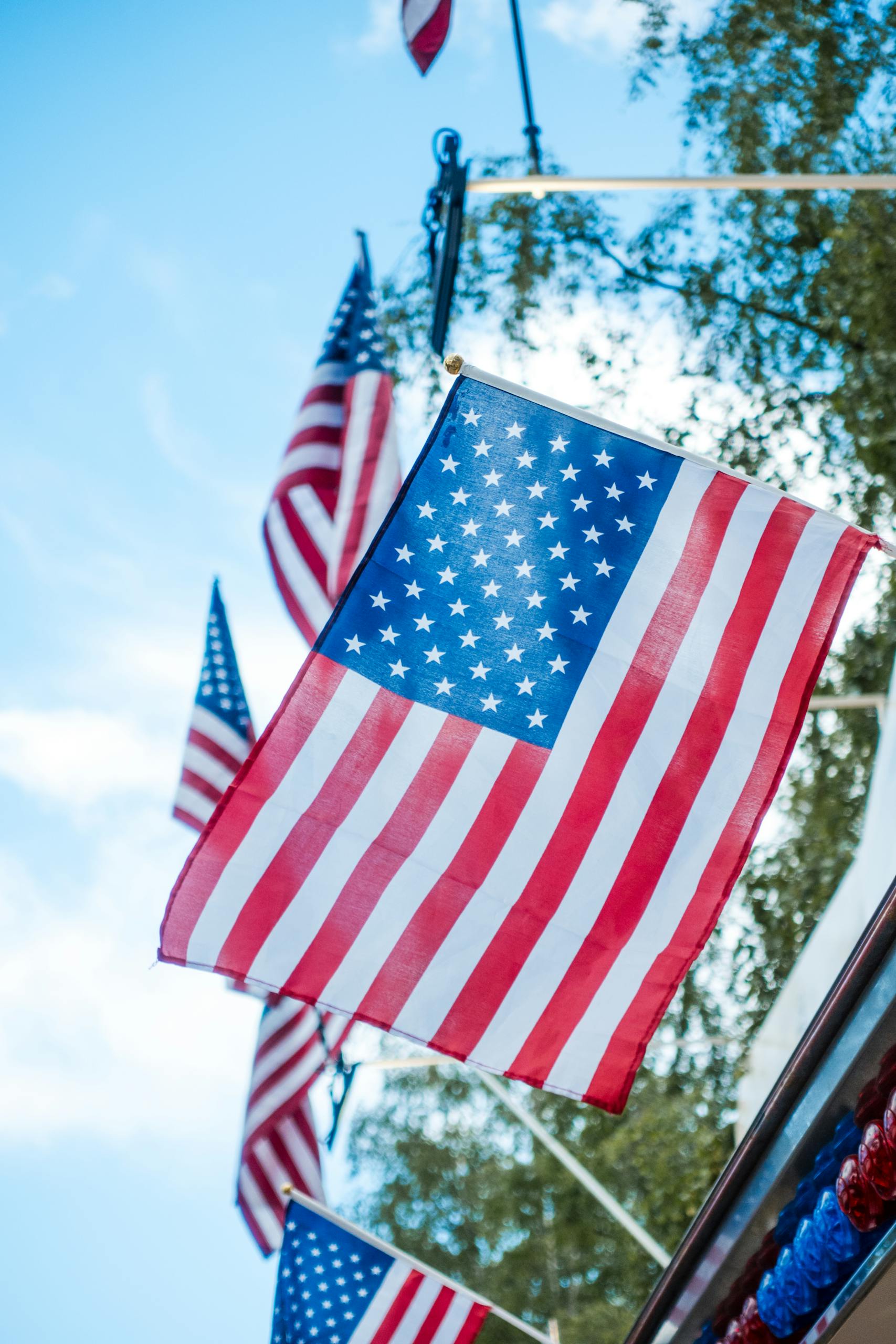 Multiple American flags waving under a blue sky, symbolizing patriotism and national pride.