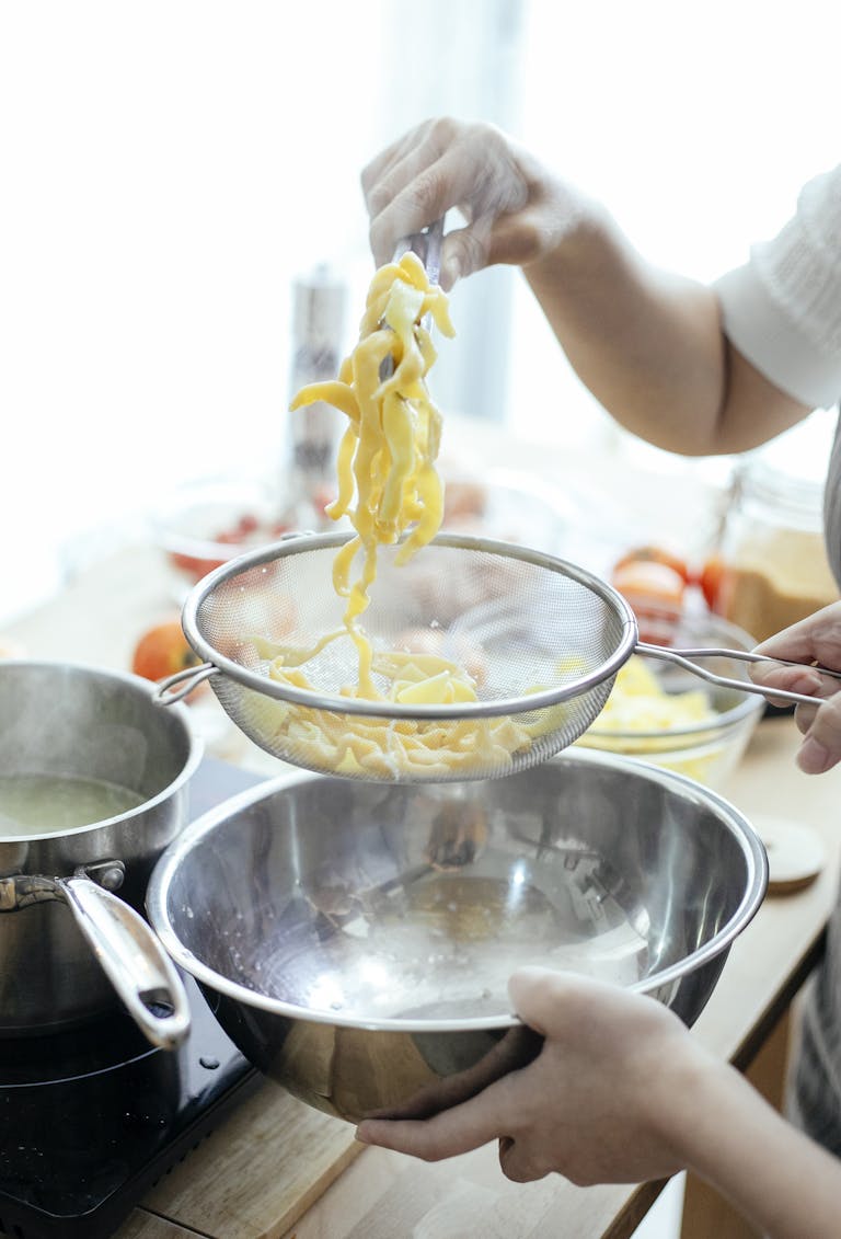 A person preparing fresh homemade pasta with steam in a modern kitchen setting.