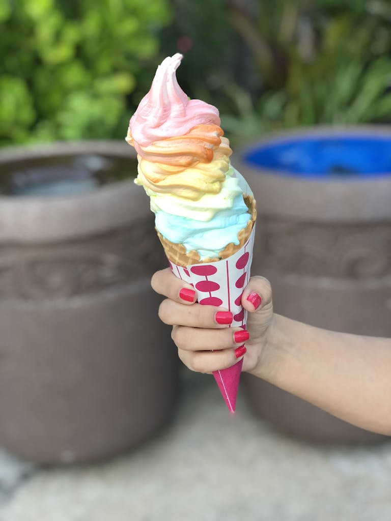Vibrant rainbow ice cream cone held outdoors, perfect for summer days in Orlando, Florida.