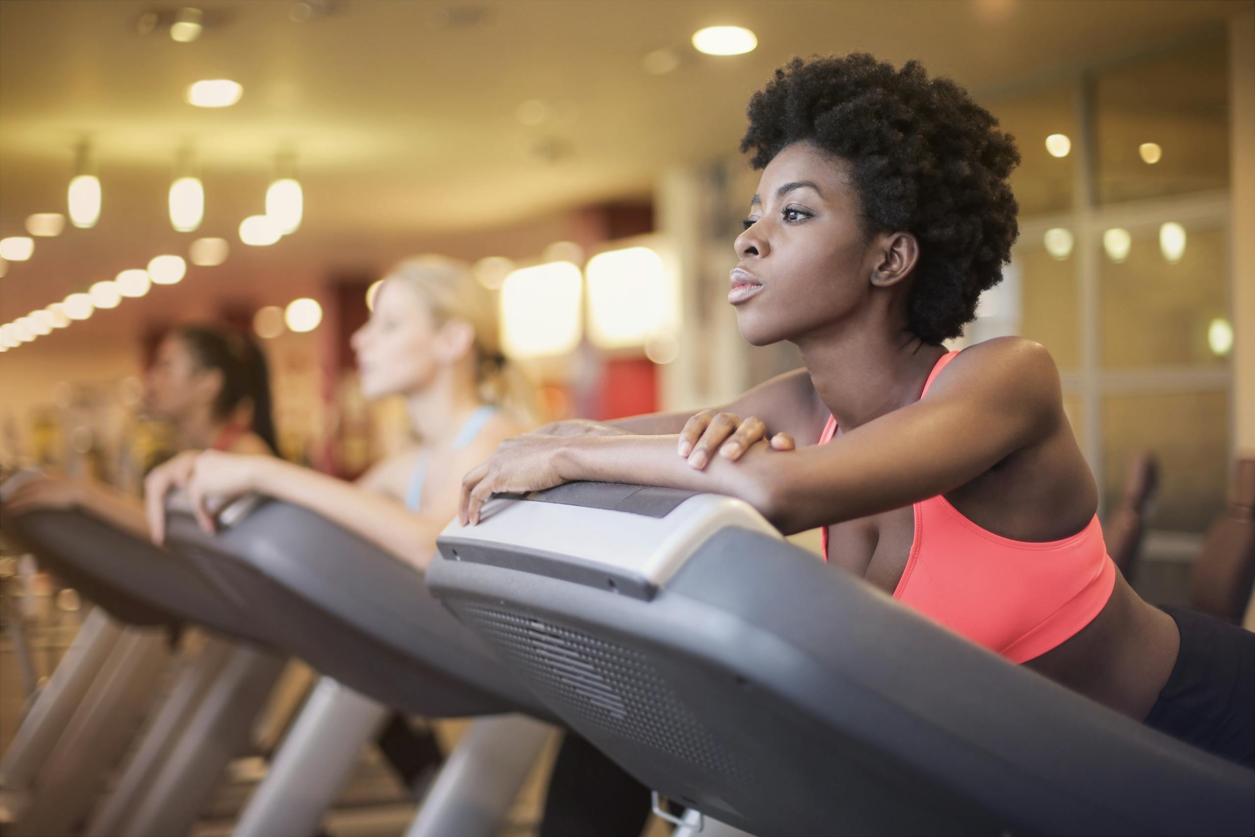 Black woman working out on treadmill in gym, showcasing healthy lifestyle and focus.