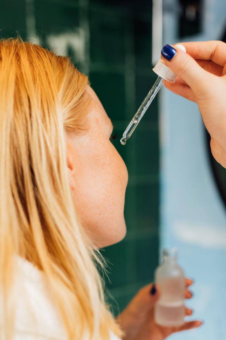 Close-up of a woman applying skincare serum with a dropper for self-care routine.
