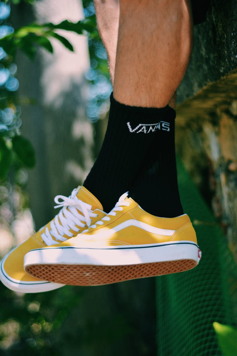 Close-up of yellow sneakers and black socks in an outdoor setting.