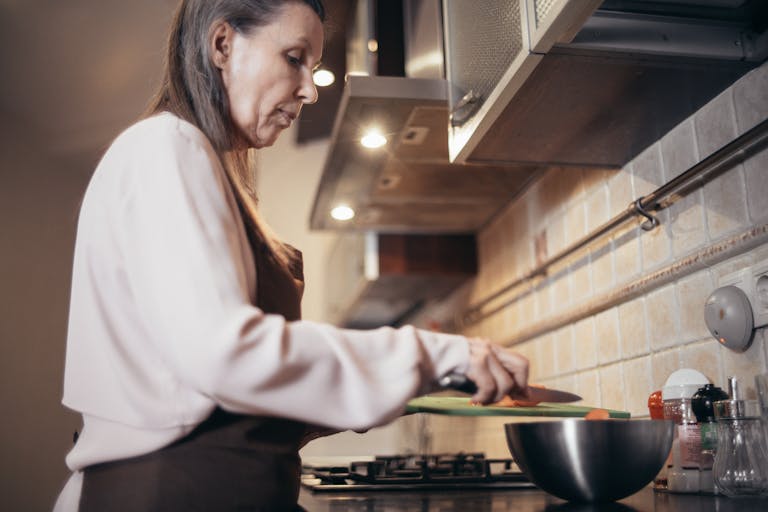 Senior woman preparing a meal in a modern home kitchen, focusing on healthy cooking.
