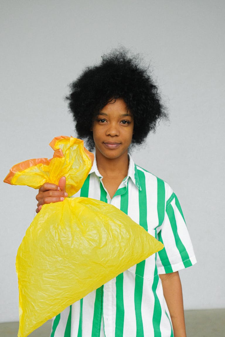 Portrait of a woman promoting sustainability by holding a reusable yellow bag.