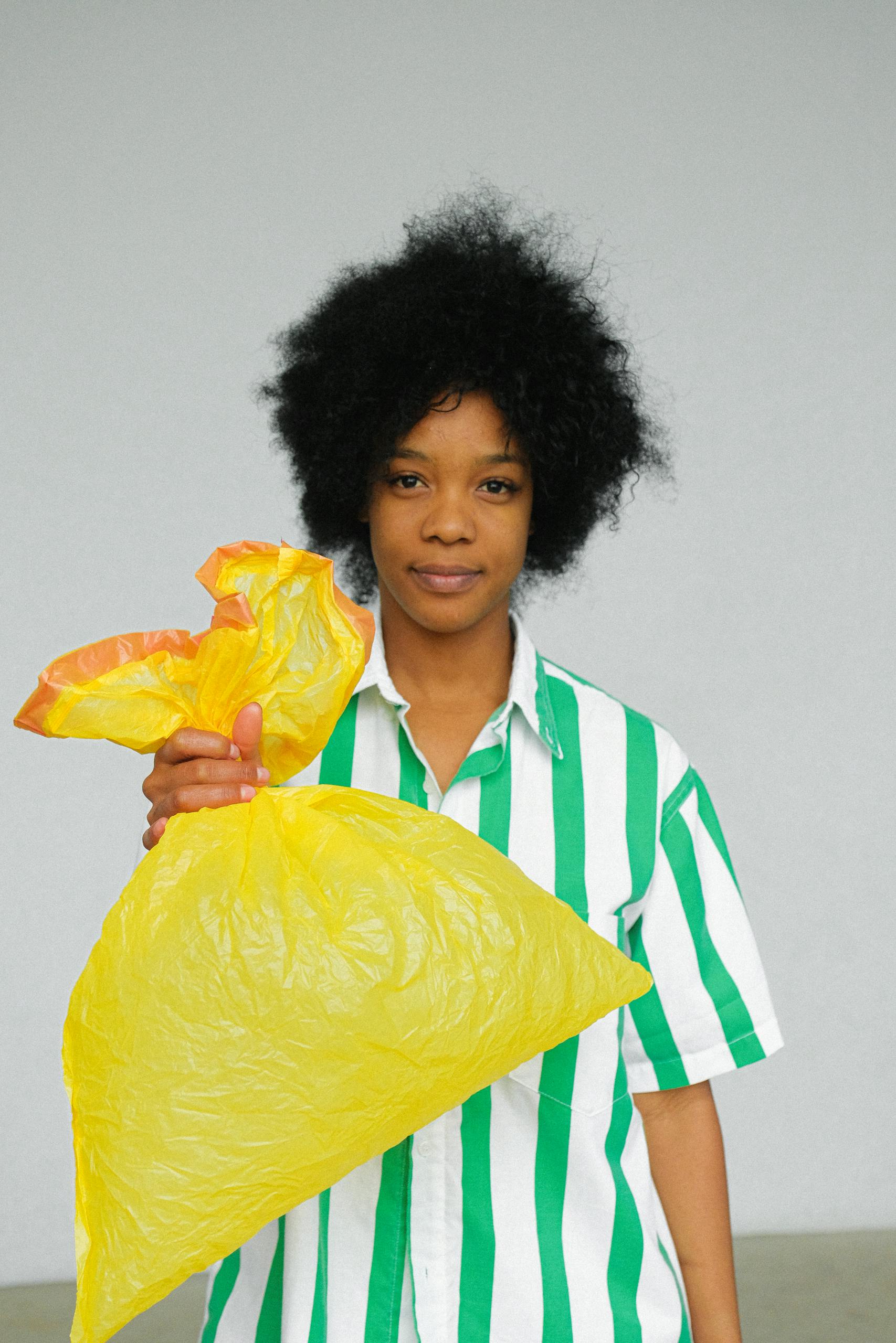 Portrait of a woman promoting sustainability by holding a reusable yellow bag.