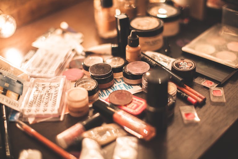 Various cosmetics and makeup products displayed on a vanity table. Ideal for beauty and fashion themes.