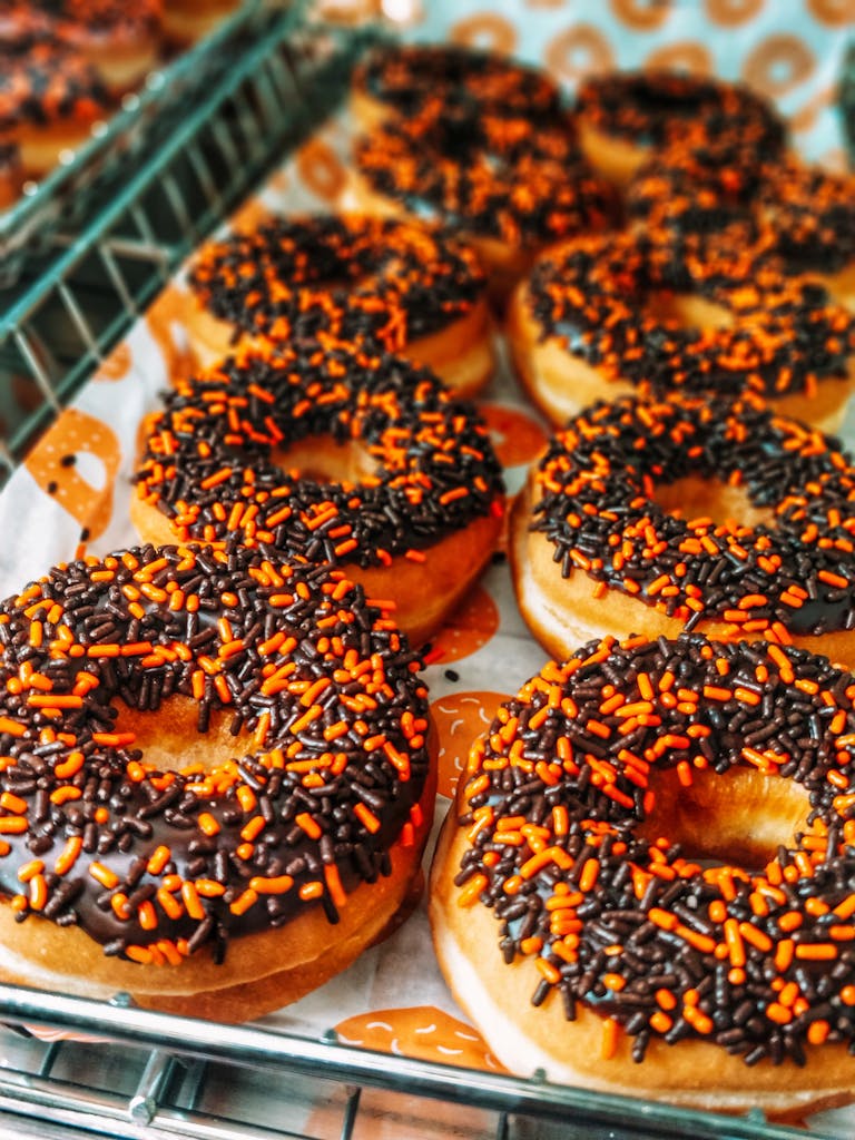 Tempting tray of chocolate donuts with orange sprinkles, perfect snack for Halloween.