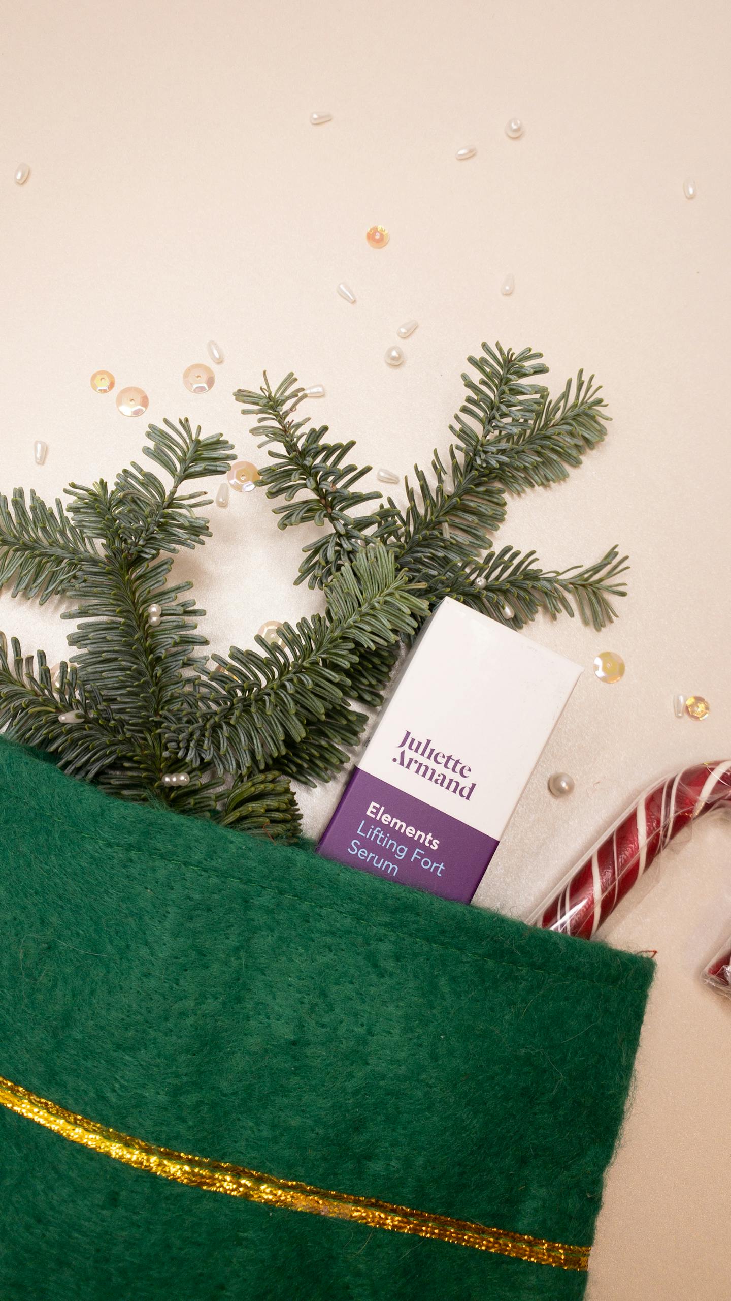Christmas stocking filled with a skincare product, candy cane, and greenery.