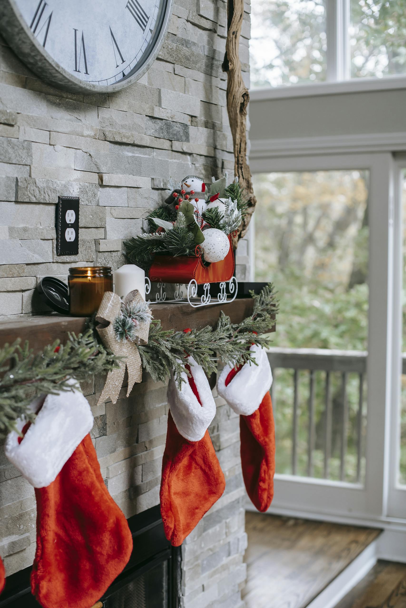 Festive Christmas mantel adorned with red stockings, greenery, and holiday decor, creating a cozy atmosphere.