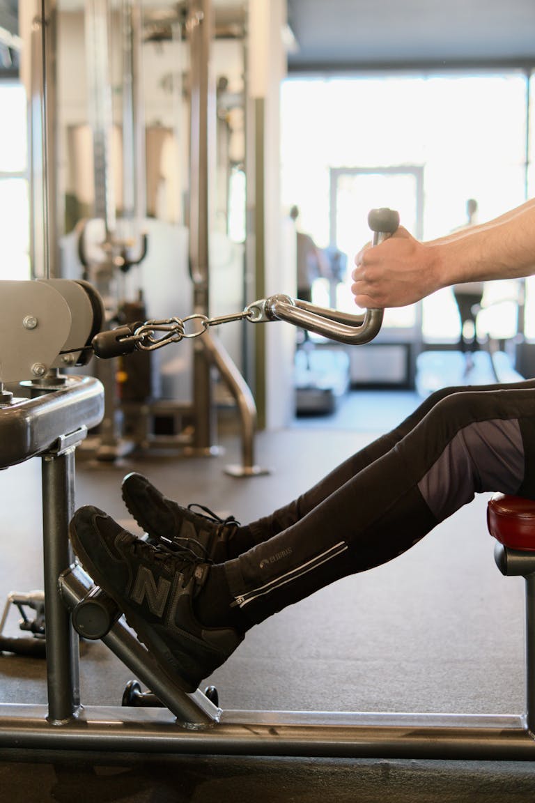 Person performing workout on rowing machine in a modern fitness gym.