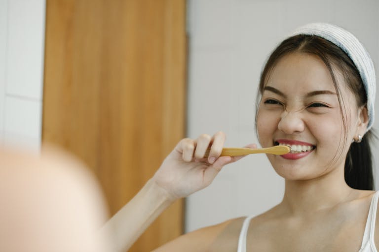 Smiling woman with toothbrush reflects joyful wellness morning routine.