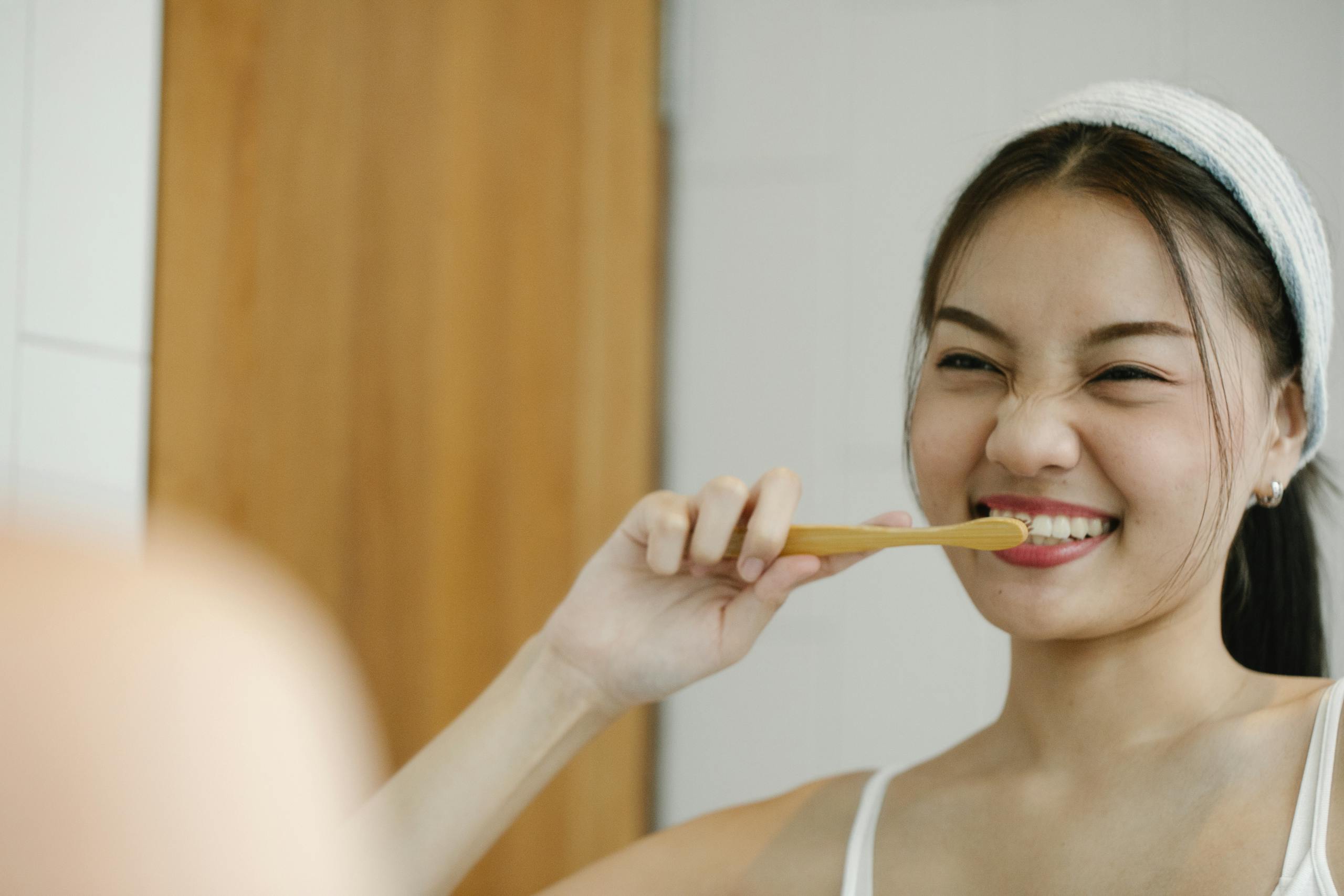 Smiling woman with toothbrush reflects joyful wellness morning routine.