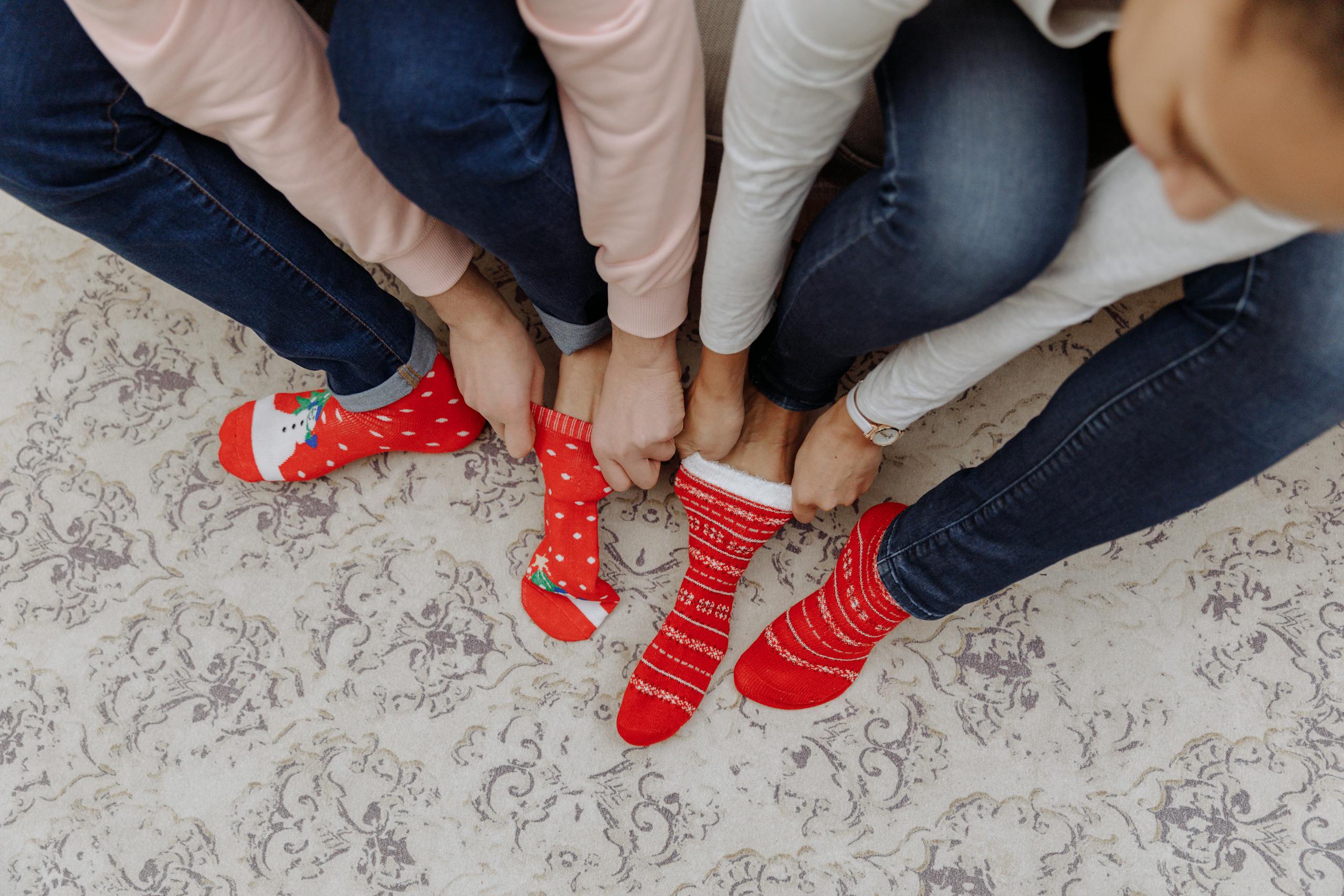 Three people wearing festive red Christmas socks indoors. Ideal for holiday themes.