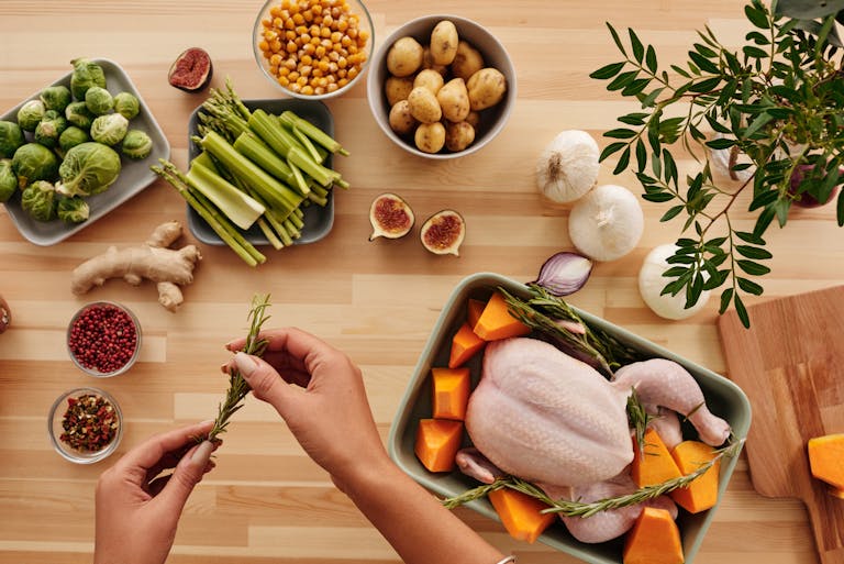 Top view of fresh ingredients and whole chicken ready for roasting, perfect for a homemade meal.