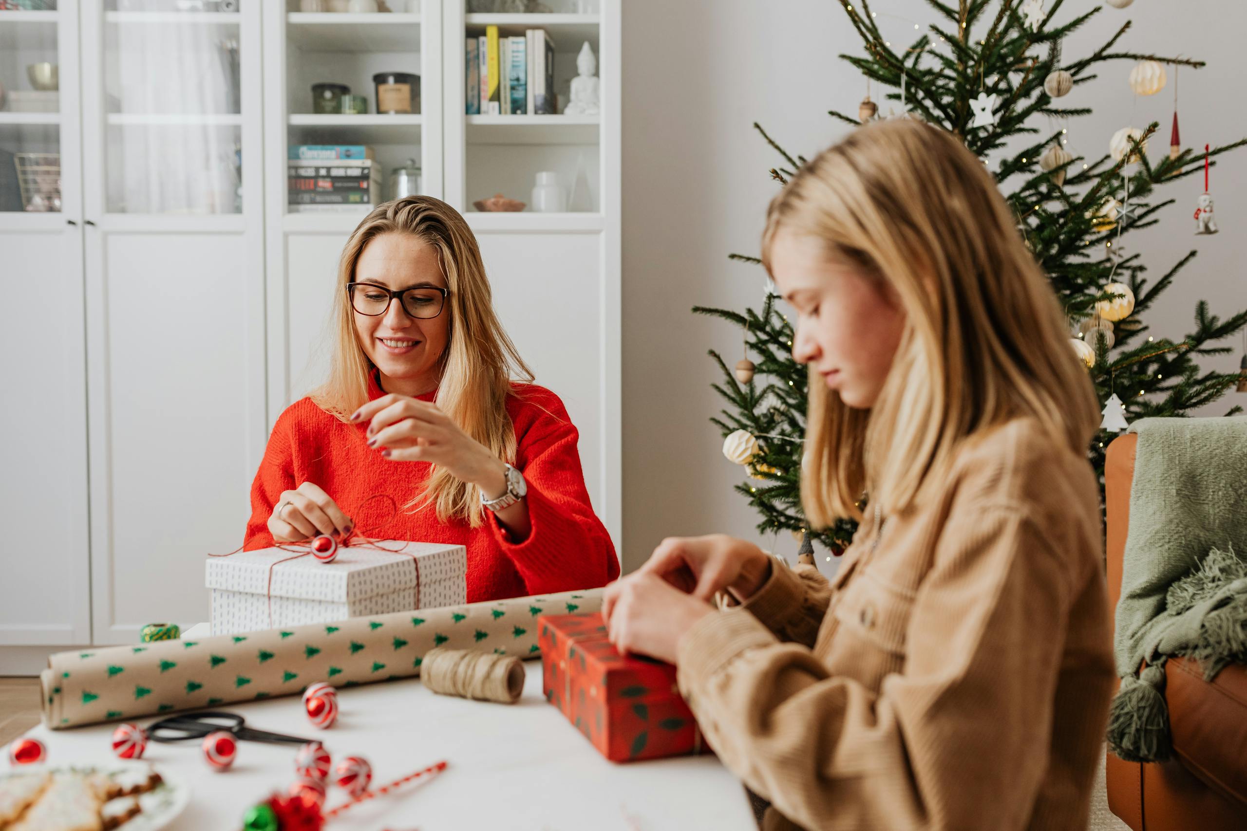 A mother and daughter wrapping Christmas gifts together at home, creating a warm holiday atmosphere.