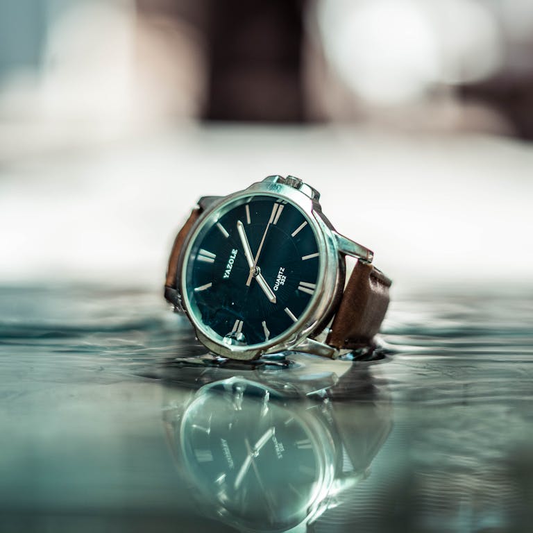 Close-up of a stylish wristwatch with a blue dial on a reflective surface.