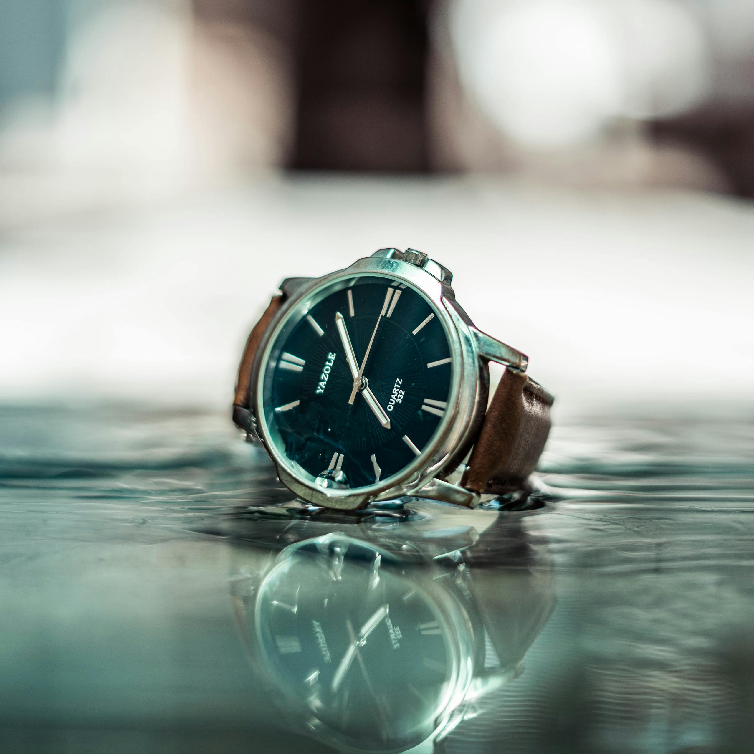 Close-up of a stylish wristwatch with a blue dial on a reflective surface.