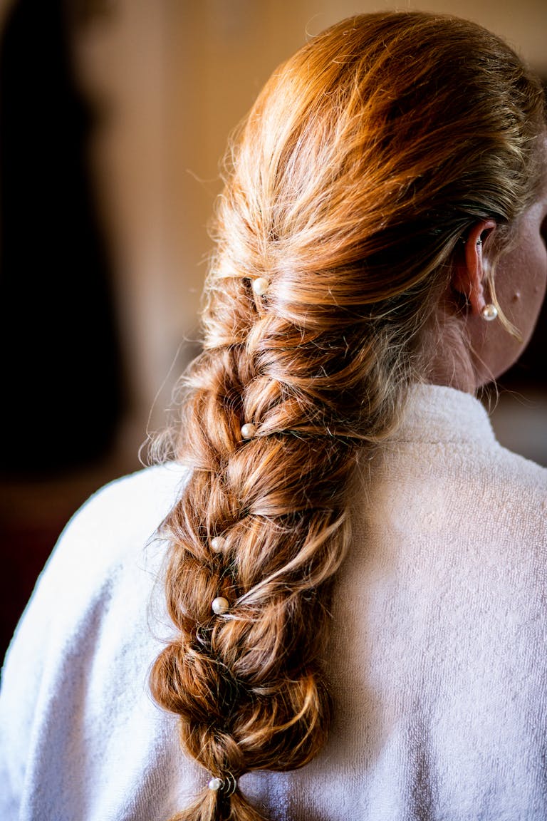 A woman with a stylish braided hairstyle featuring long, brown hair, captured indoors with soft lighting.