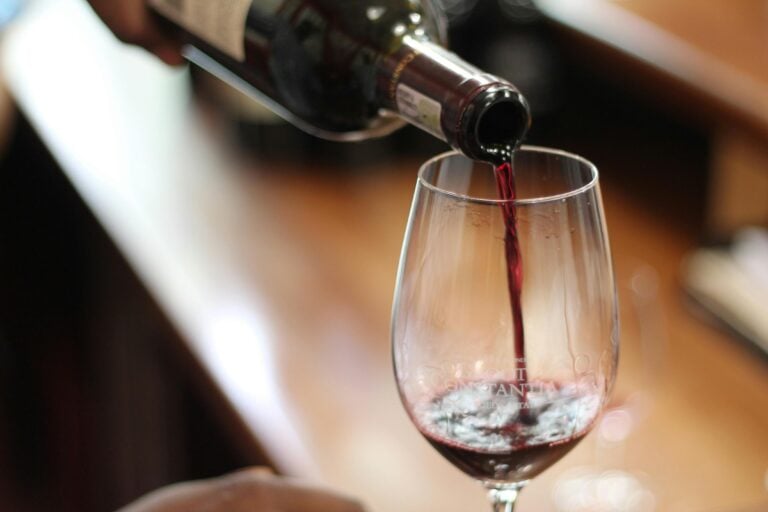 Close-up of red wine being poured into a glass with a selective focus and blurry background.