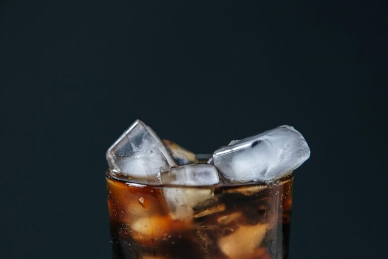 Extreme close-up of a fizzy cola drink with ice cubes, perfect for a refreshing treat.