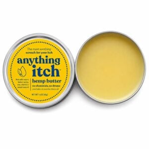 Open tin of Anything Brands Anything Itch balm beside its yellow lid