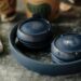 Dark blue JBL wireless headphones beside a smartphone and coffee on a table.