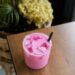 Refreshing pink iced beverage with straw on a wooden table in a cozy setting.