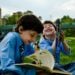 Two brothers enjoying a sunny day in the park, reading and laughing together.