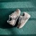 Overhead shot of New Balance sneakers on a teal textured surface under natural light.