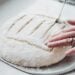 A detailed view of hands scoring bread dough for baking, showcasing artisanal bread preparation.