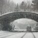A winter storm covers a Swiss bridge in snow, creating a beautiful yet hazardous landscape.