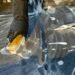 A detailed view of cleaning in progress, focusing on a gloved hand using a brush with detergent on a surface.