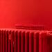 A vibrant red radiator against a matching wall captures minimalist and modern interior design.