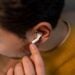 Close-up of a man wearing wireless earbuds in a yellow sweater, focusing on tech.