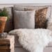 Warm and inviting living room with a focus on soft textures, featuring a sofa with fur throws and decorative pillows.